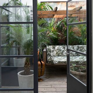garden area with sofa and plant pots with glass door