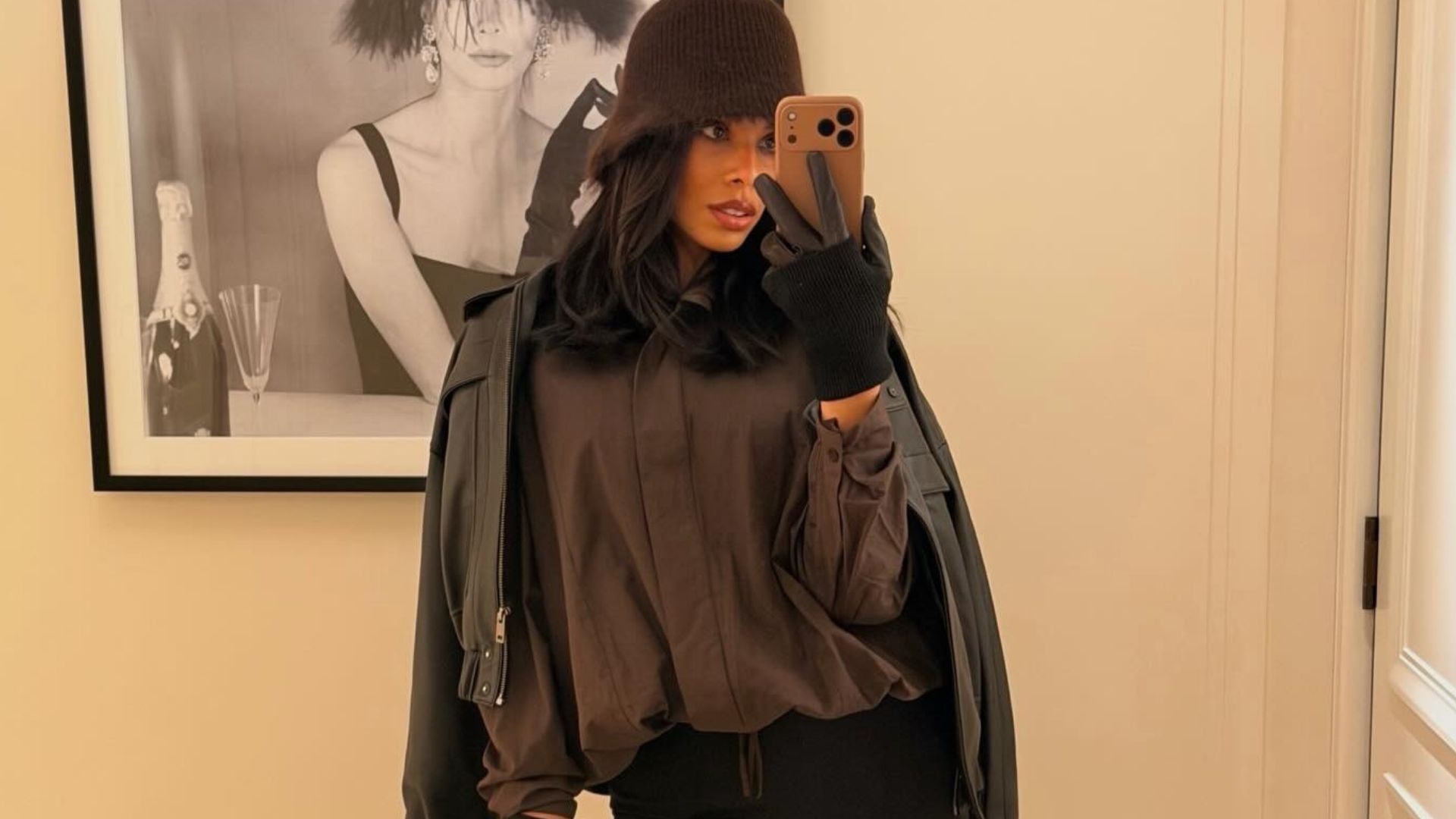 Rochelle Humes takes a mirror selfie wearing a brown shirt, black leather jacket, flared jeans and almond-toe boots.