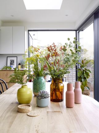 Colourful vases and flowers and plants on a dining table