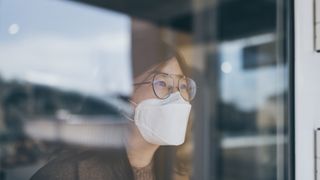 How do air purifiers work? Image of person with mask looking out of window