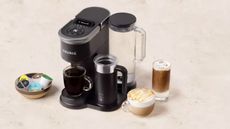 Keurig K-Supreme Smart Coffee Maker on a marble countertop with two cups of coffee beside it as well as some coffee pods
