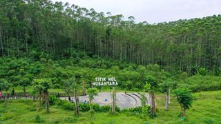 An aerial image of a tropical landscape with a small paved clearing and a sign that reads 