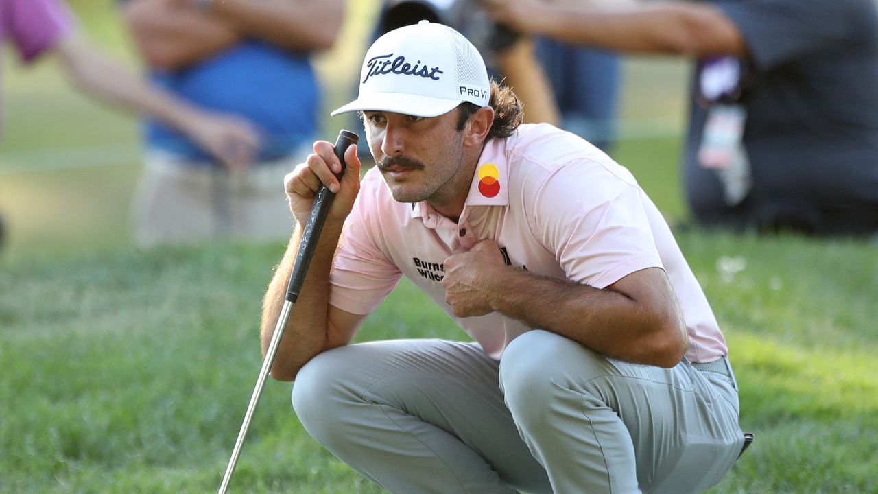 Max Homa crouches to read a putt 