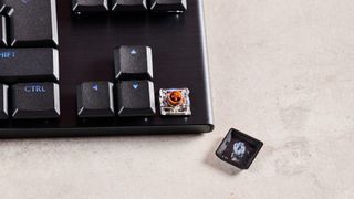 Close-up of arrow keys on Logitech G915 X, with one keycap removed, exposing switch beneath