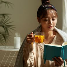 Coming off the pill: A woman reading a book with a cup of tea