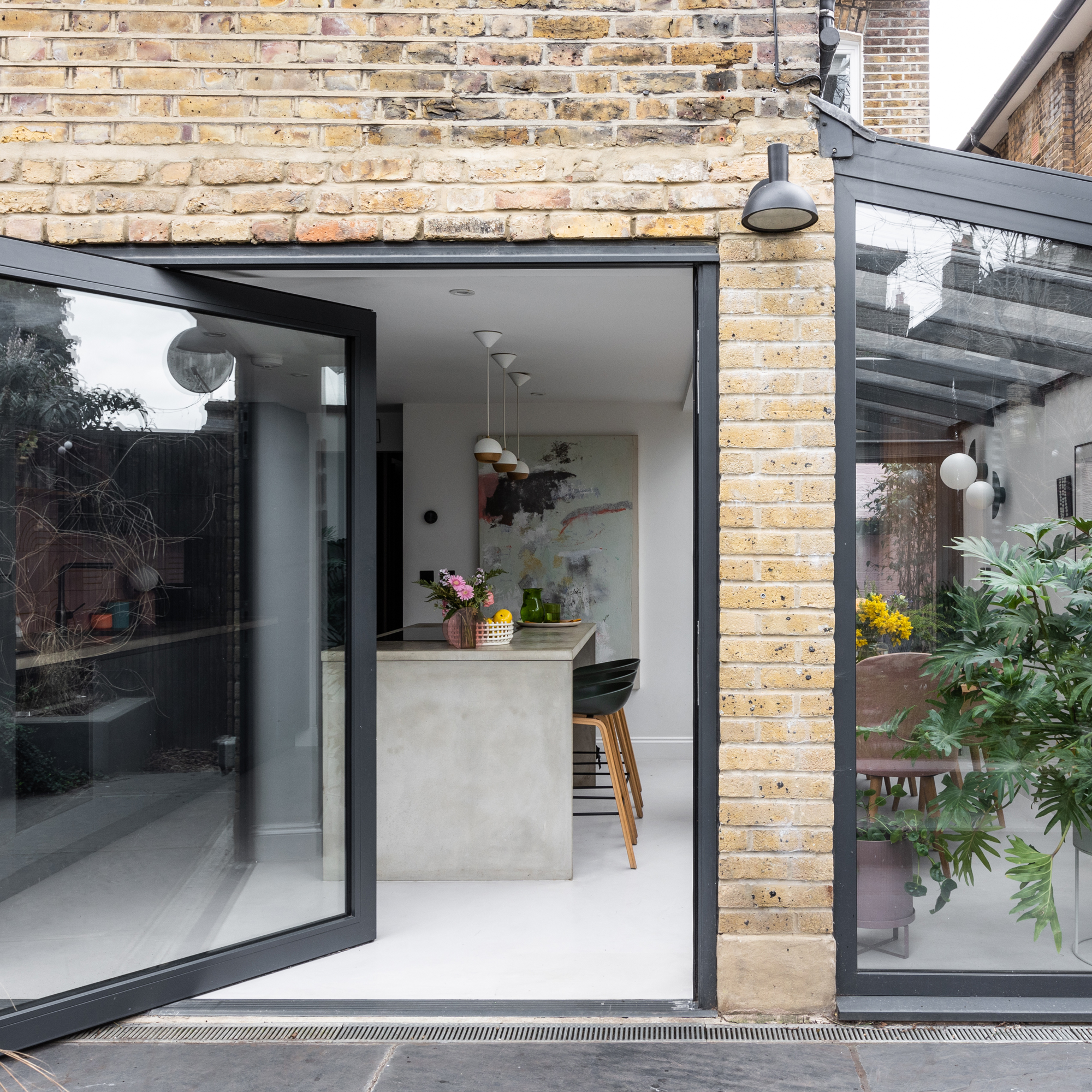 exterior view of a house looking into a kitchen diner with a pivot door and glazed side return