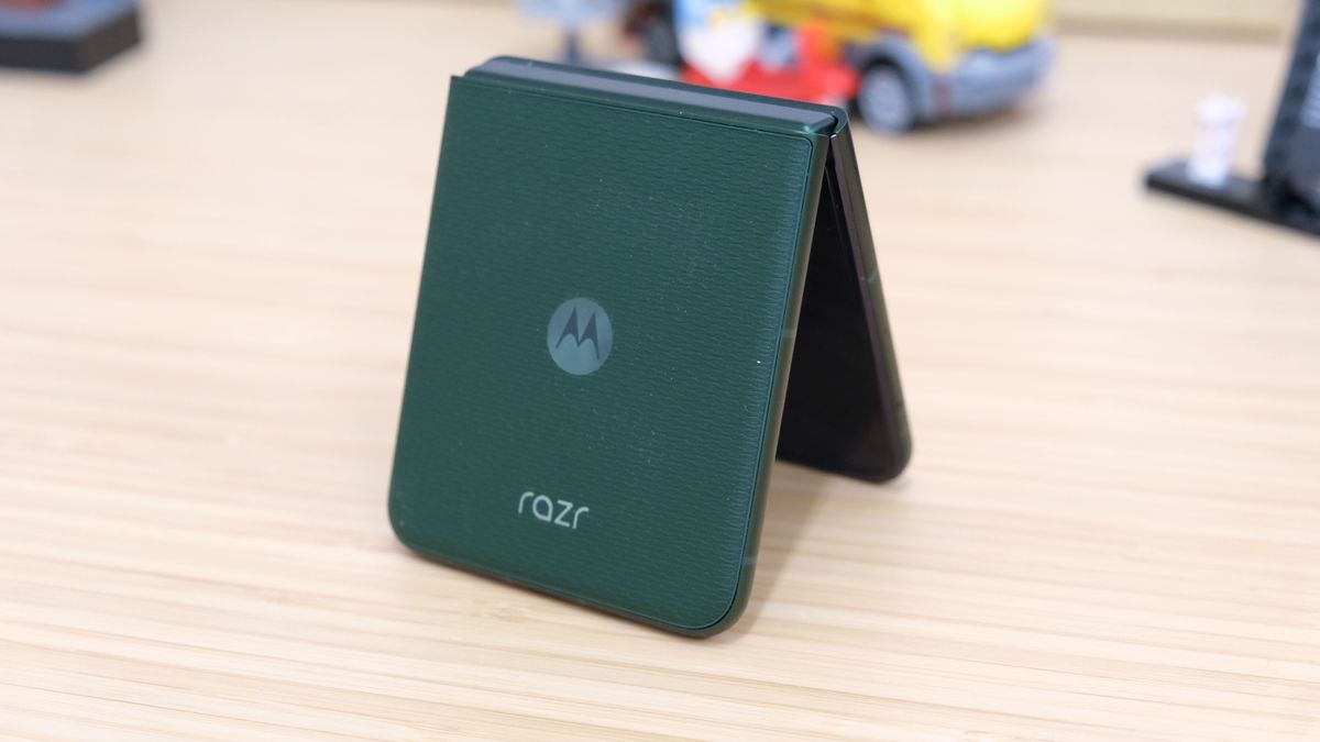 The Motorola Razr Plus 2026 in the hand and on a wooden table