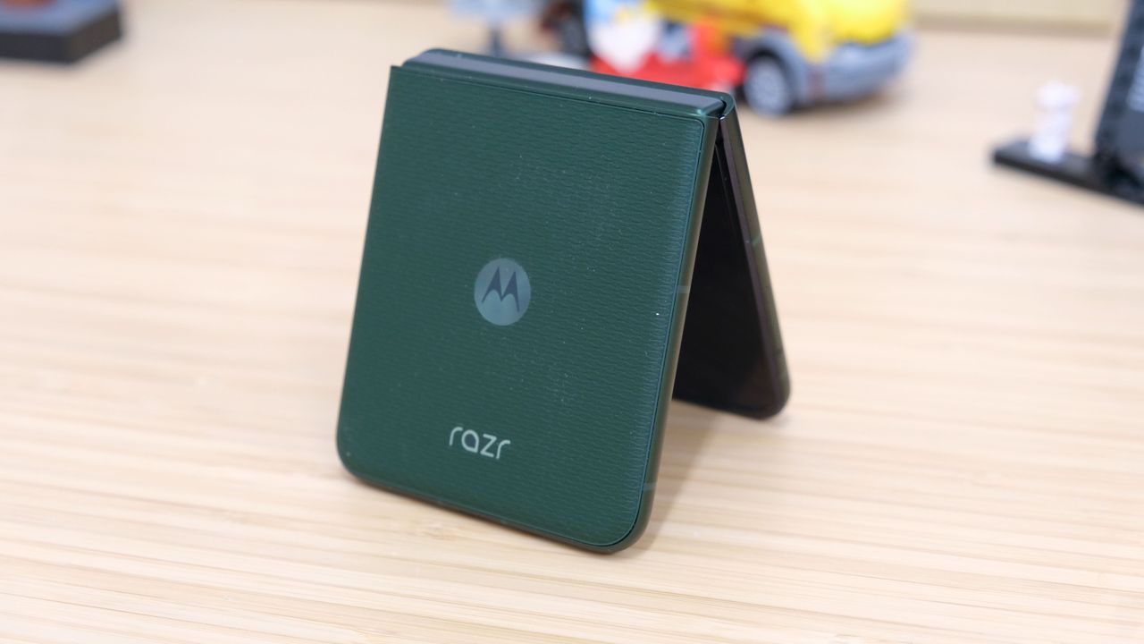 The Motorola Razr Plus 2026 in the hand and on a wooden table