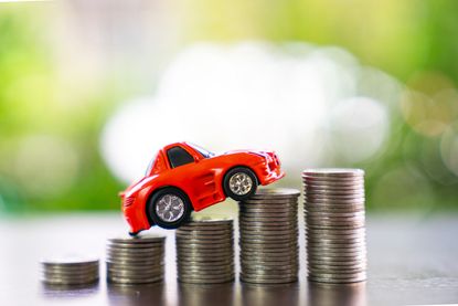 Red toy car on top of stacks of coins