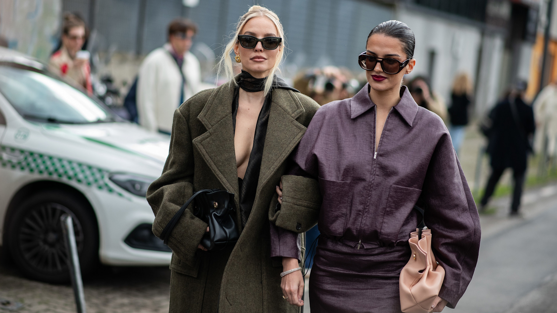 two fashion week attendees wearing sunglasses and green and dark red coats