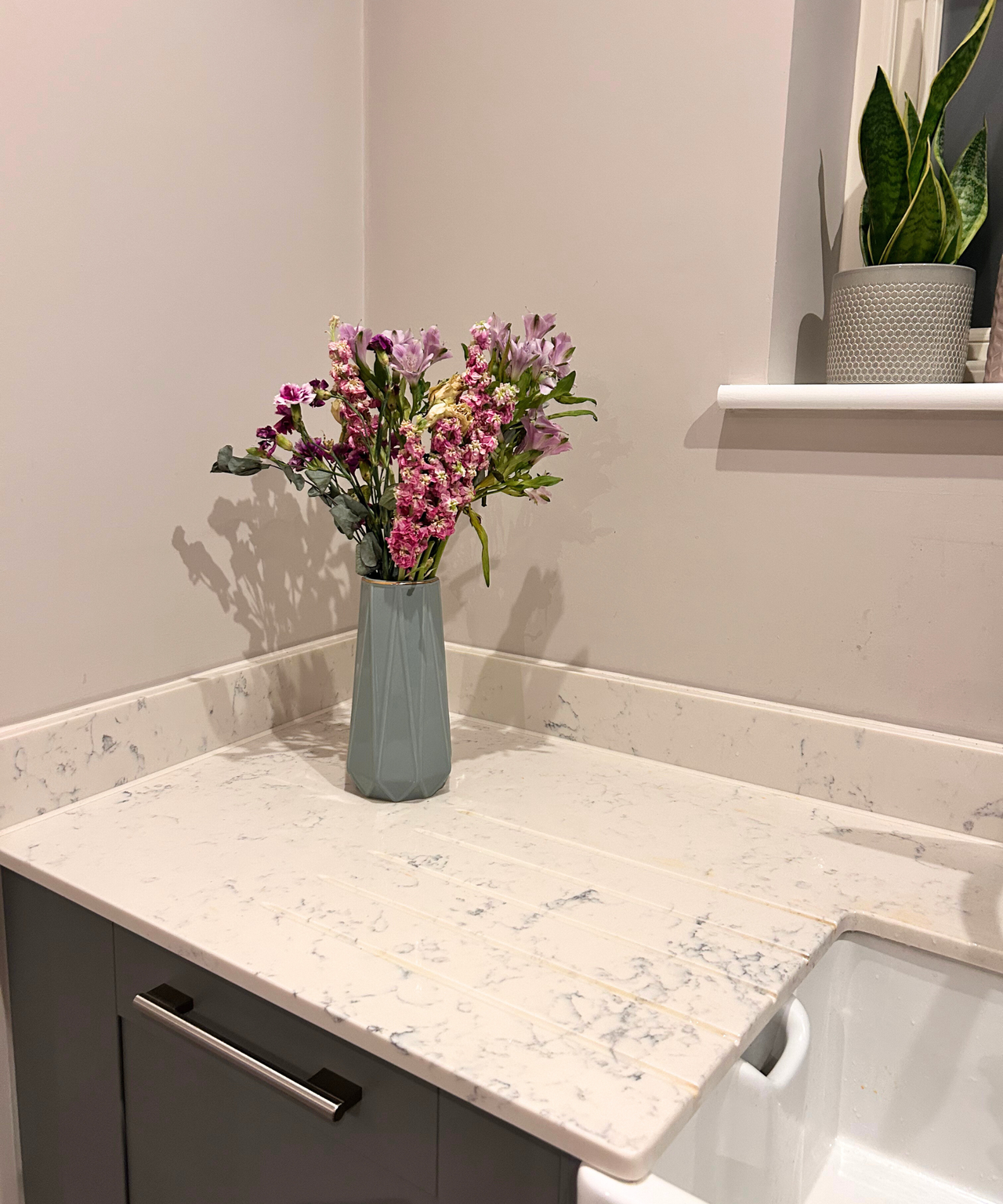 After - a kitchen countertop with flowers in a green vase on it