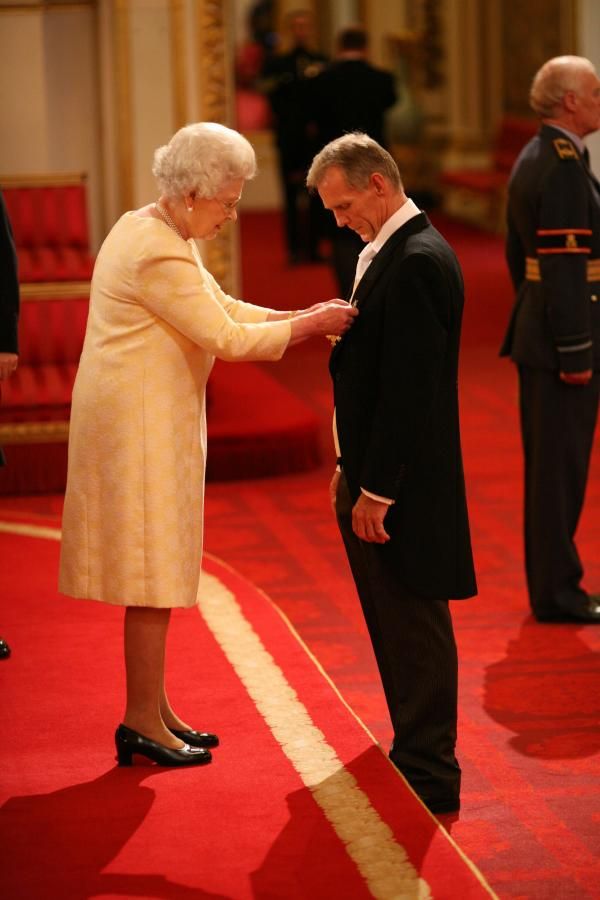 Queen Elizabeth II awards the MBE to GB cycling's Performance Manager Shane Sutton.
