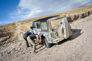 Two women fixing a tyre on Jeep in desert