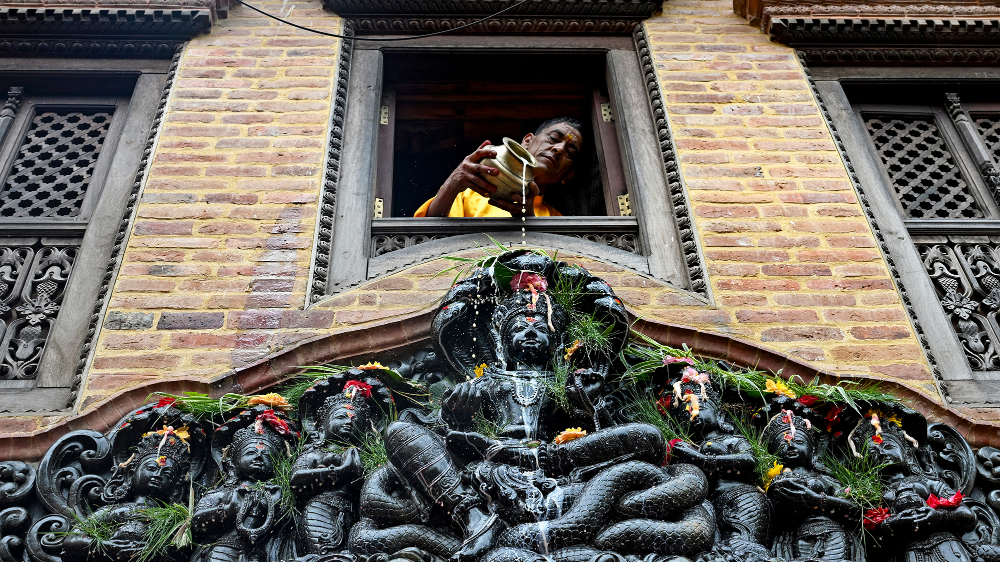 A devotee pours milk over a statue of the Hindu goddess Manasa in Bhaktapur, Kathmandu