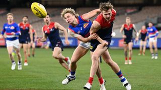 James Jordan of the Demons handballs whilst being tackled by Cody Weightman of the Bulldogs