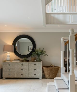 country style entrance hallway with large round mirror and cream tiled floor