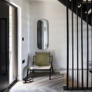 hallway with a black front door a long mirror with a chair underneath