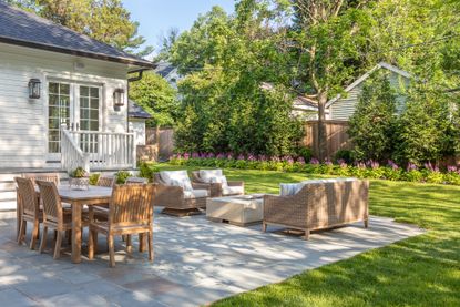 outdoor lounge area with large lawn and hydrated flower beds