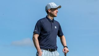A golfer in a navy Ping Mr Ping II Polo Shirt