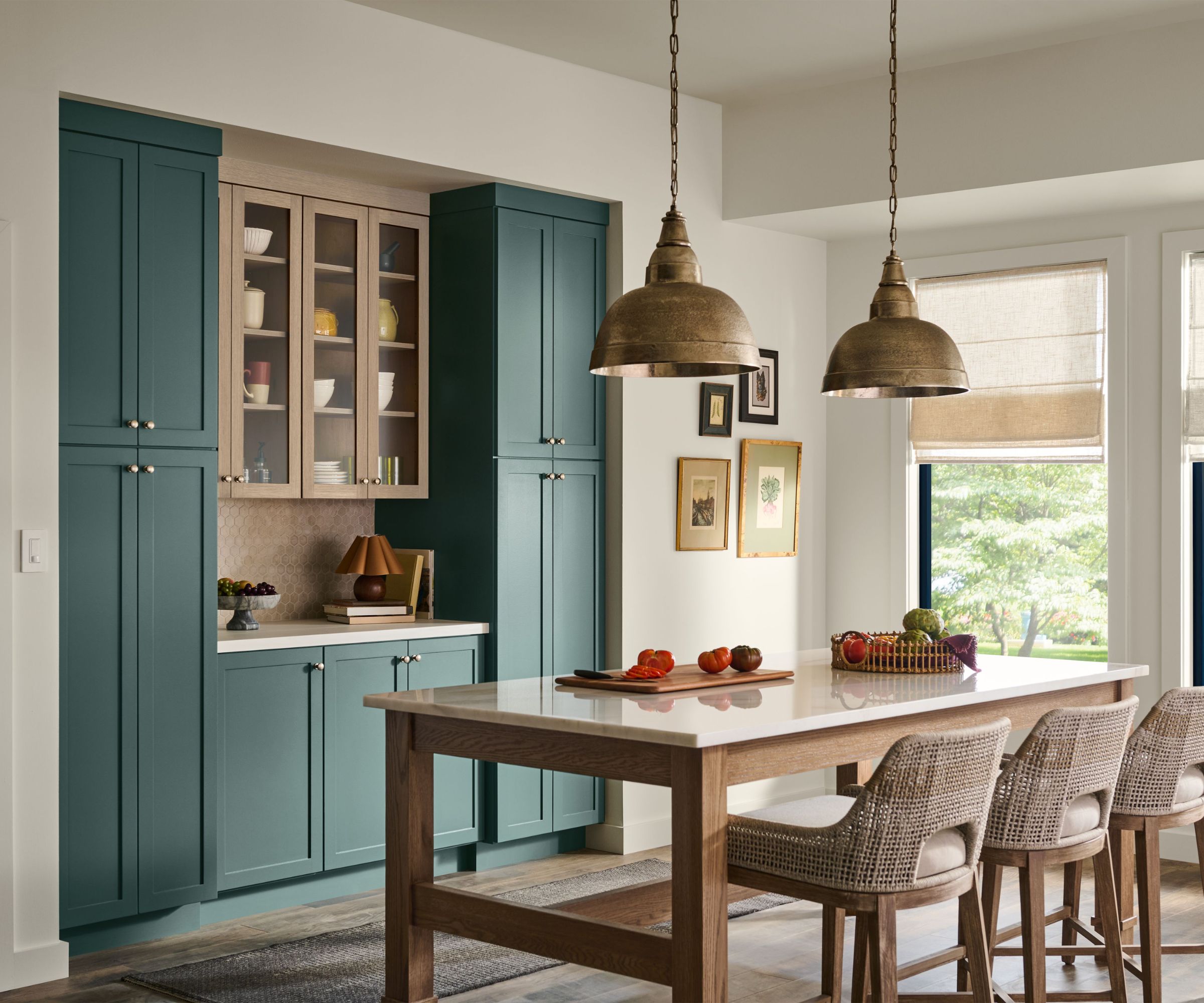 Kitchen with island and rattan stools, jade painted cabinets, gold pendant lights