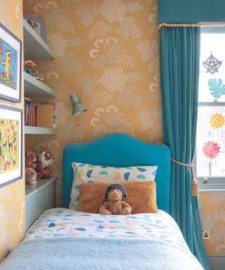 A kid's bedroom with bright orange wallpaper and a blue bed frame