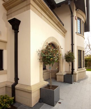 Large traditional-style rendered property with cream render and black hopper head and downpipe from Yeoman Rainguard