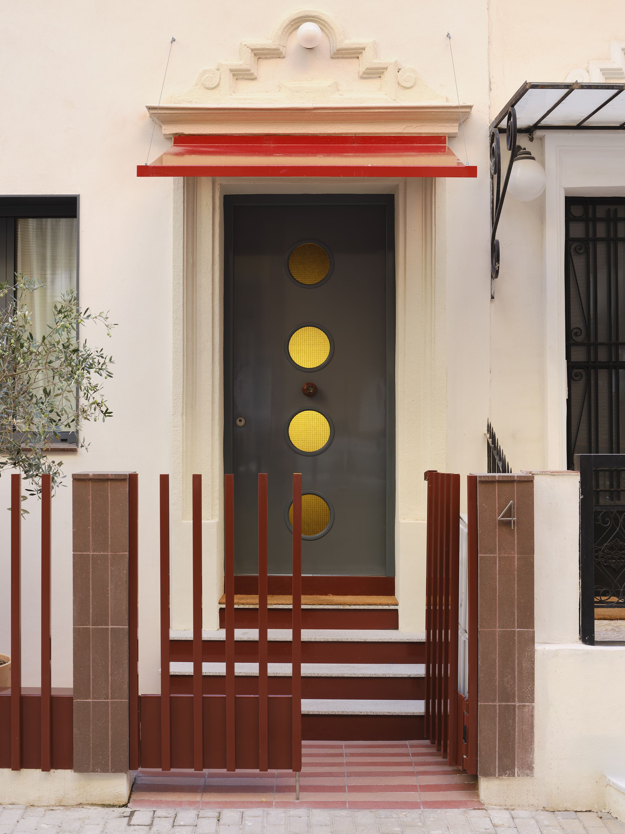 a modernist front door with circular window cut outs and red railings
