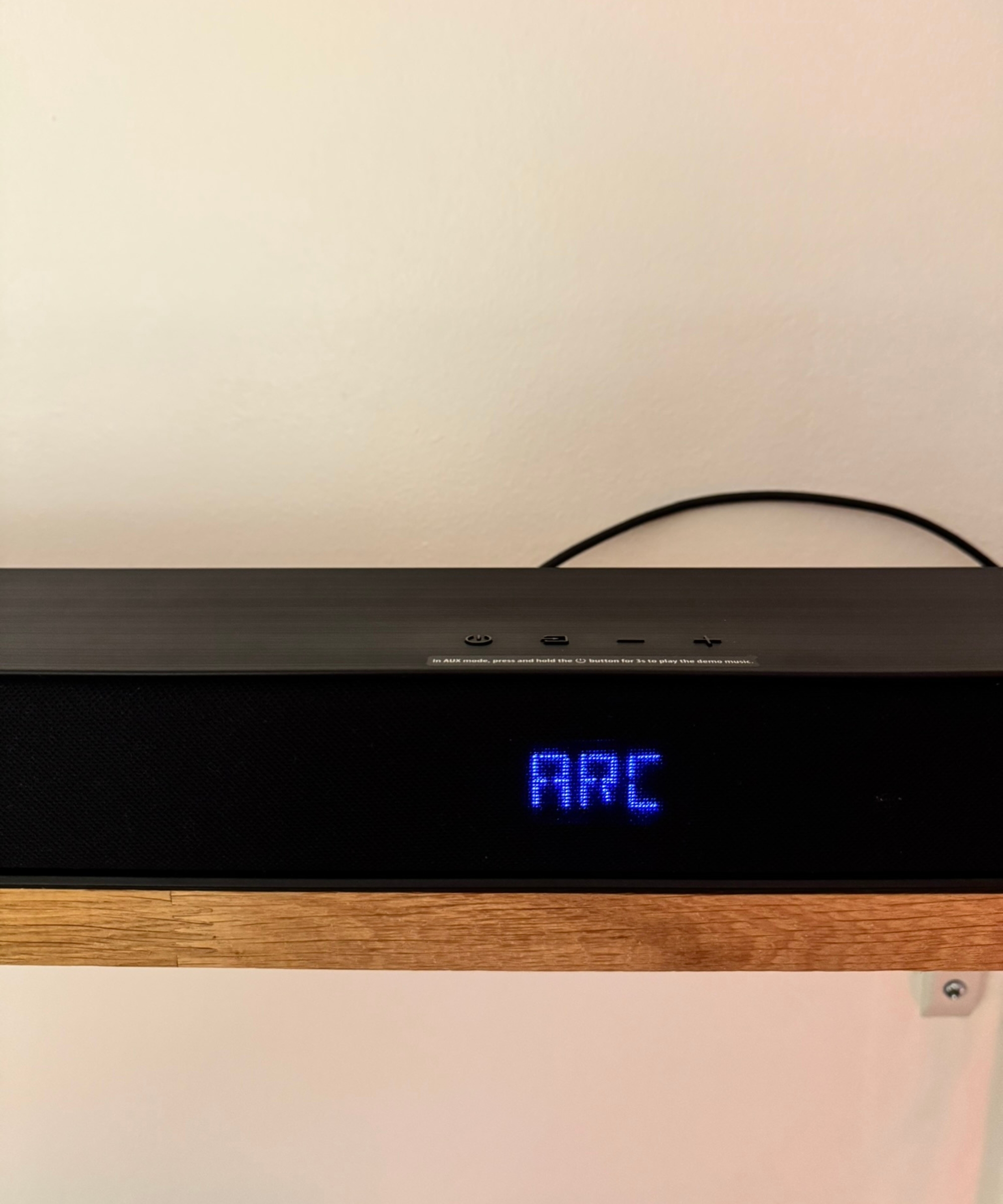 Hisense AX5140Q soundbar on wooden shelf, with blue lit-up text displaying 'ARC'.