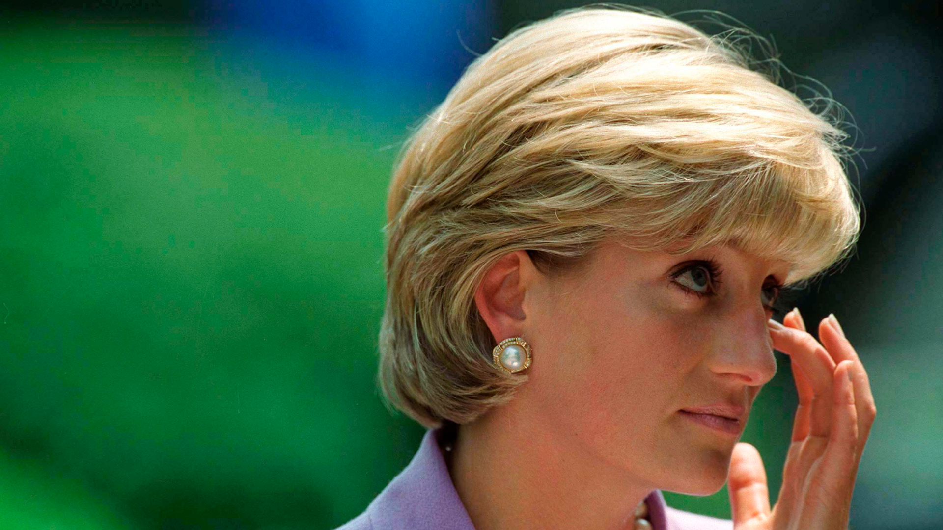 Princess Diana wearing a purple suit and rubbing her eye