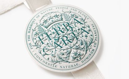 Close-up of the paper Terra Carta Seal by LoveFrom, with green embossed type on white paper