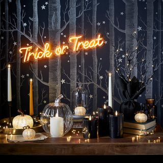 Halloween table with pumpkins, candles and neon trick or treat wall light