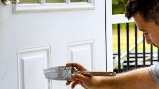 Person painting wooden front door white