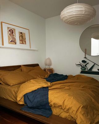 A bedroom with a pendant lantern and a set of stackable stools used as a nightstand in the corner