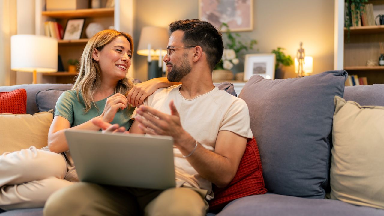 A couple give each other a loving expression as they sit on the sofa together.