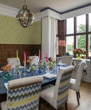 Traditional dining room with green wallpaper, wood paneling and spherical pendant light by Kelling Designs