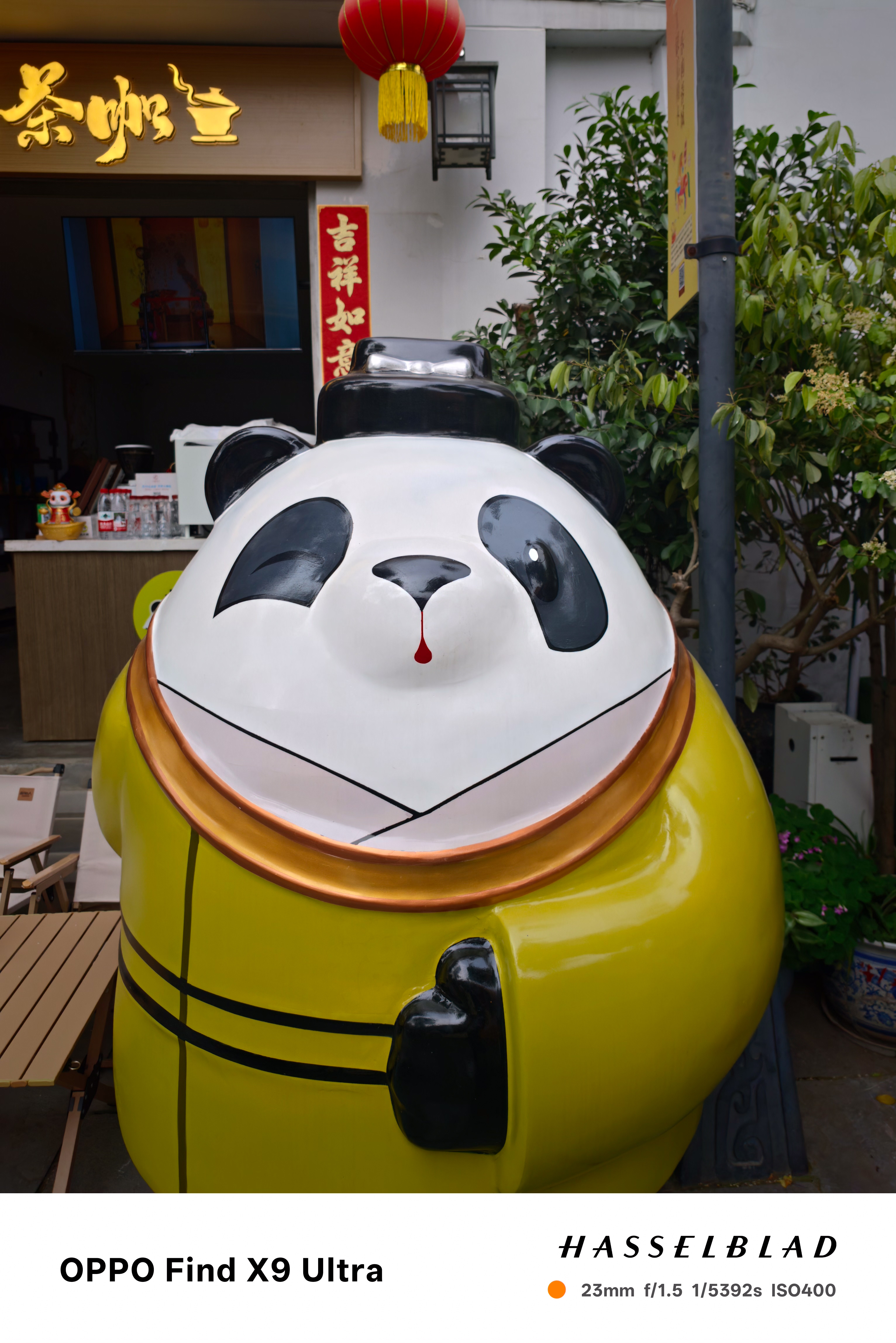 Large panda statue in yellow outfit outside a storefront