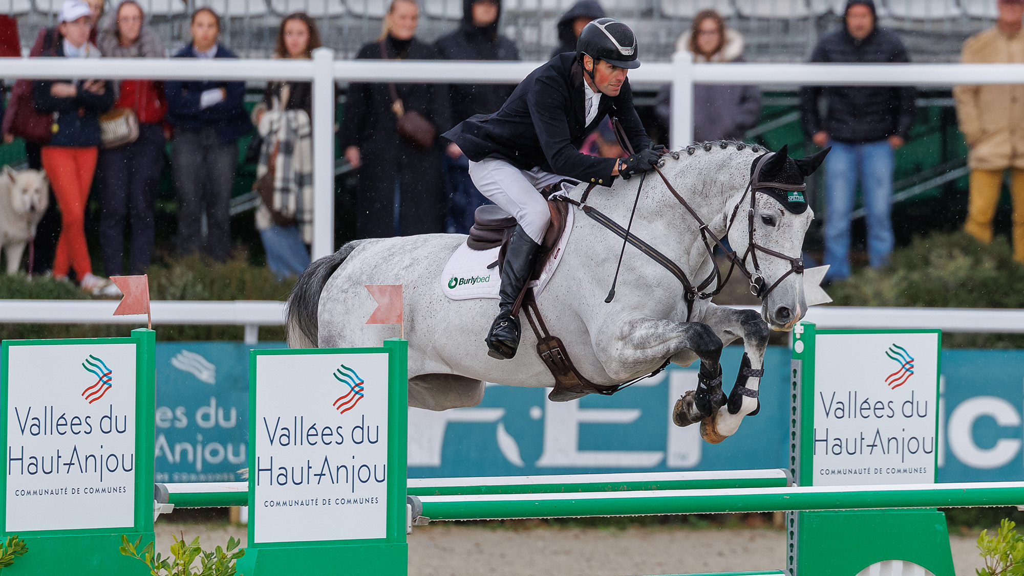 Hector Payne, a rider in a dark jacket, rides grey horse Bueno over a green and white showjump at Le Lion d&amp;lsquo;Angers 2026