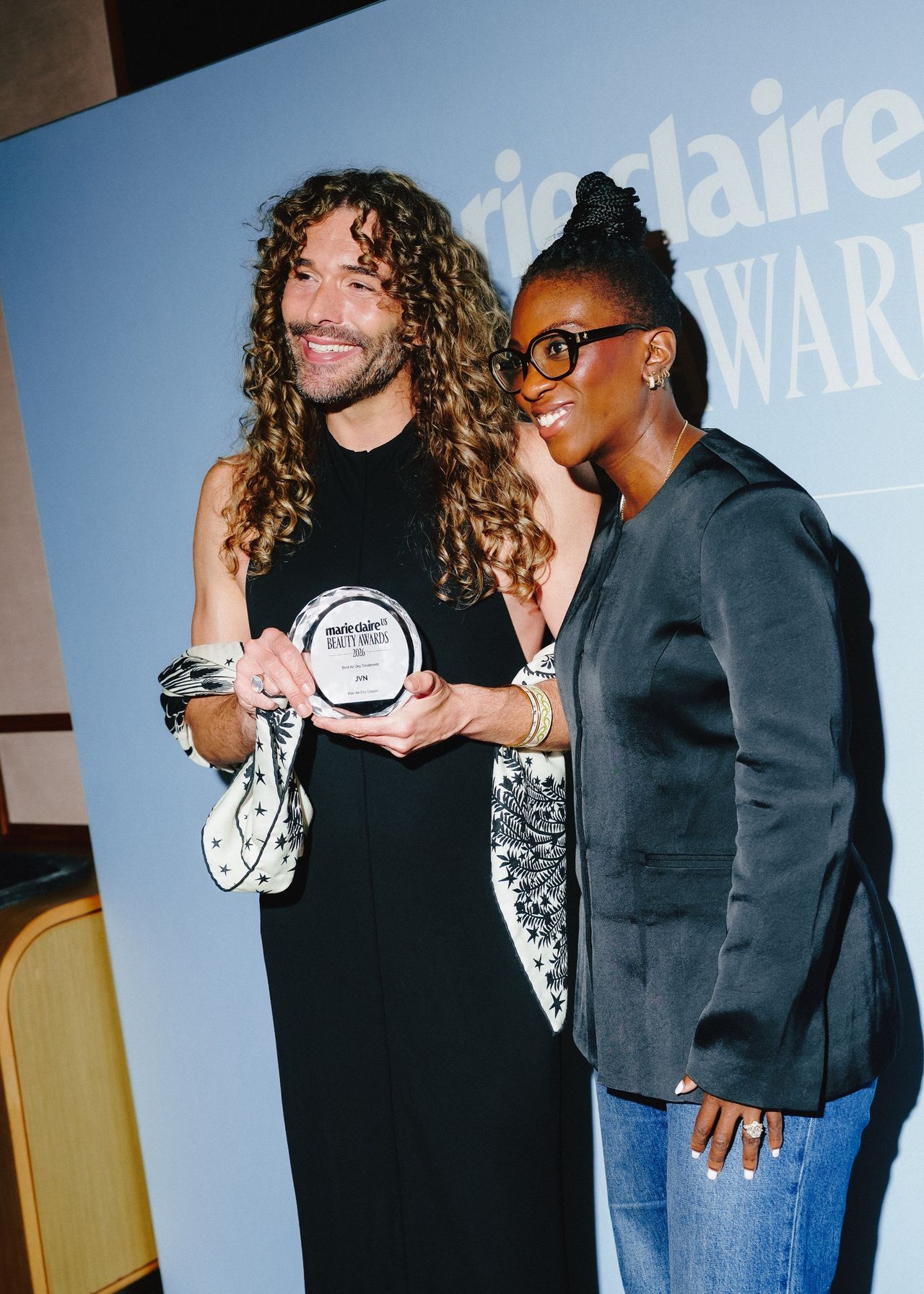 a white man and a black woman in front of a blue step and repeat