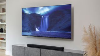 Sony HT-A5000 soundbar sitting on a wooden table, with TV wall mounted above it