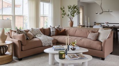a soft neutral living room with marble fireplace and a large pink section sofa