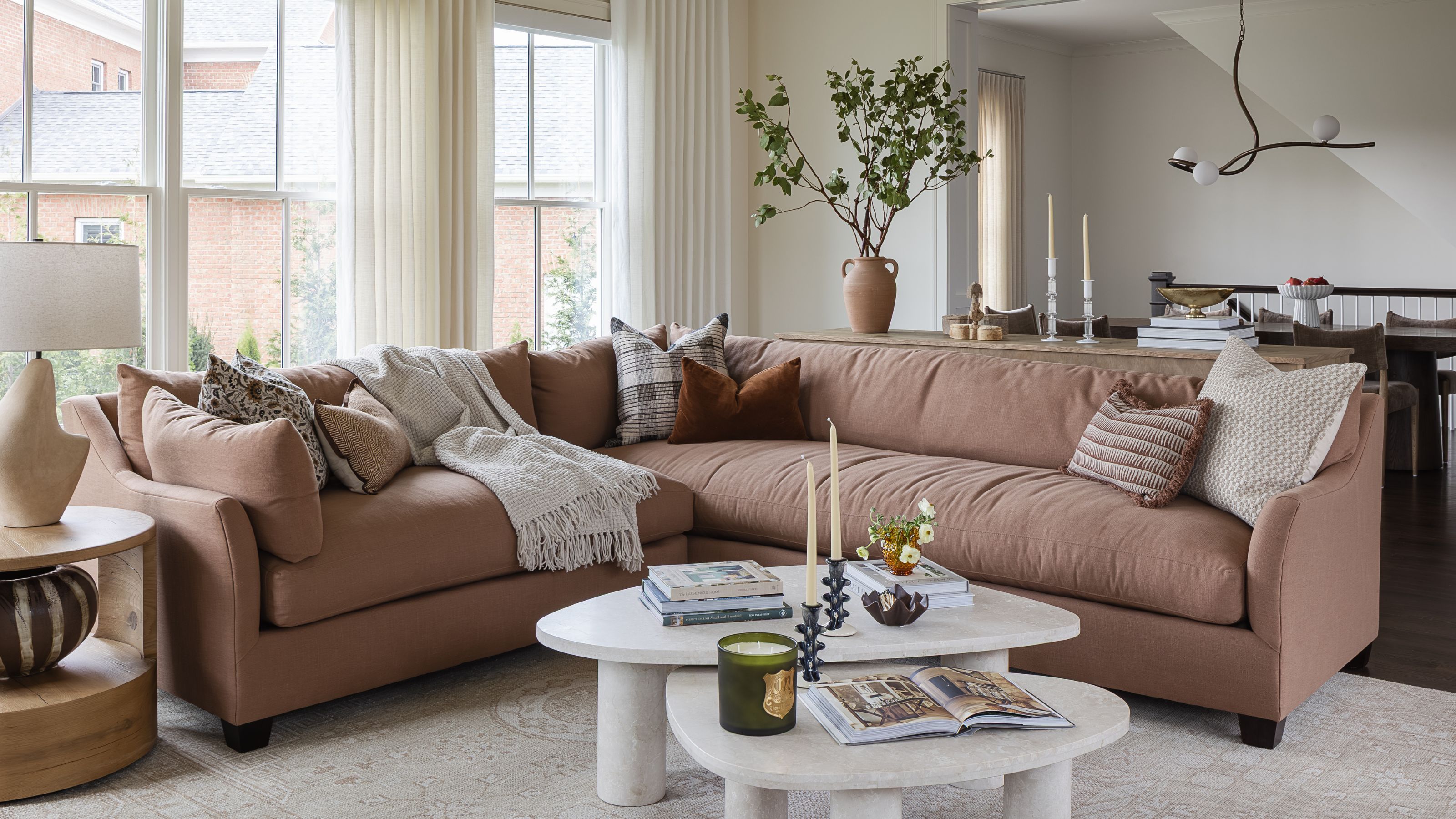 a soft neutral living room with marble fireplace and a large pink section sofa