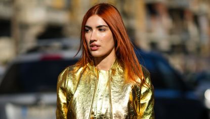 Patricia Manfield wears a gold shiny leather zipper cropped jacket from Fendi, a matching gold shiny leather ruffled knot slit short dress from Fendi, a gold shiny leather Nano Fendigraphy handbag from Fendi, outside the Fendi fashion show, during the Milan Fashion Week Fall/Winter 2022/2023 on February 23, 2022 in Milan, Italy