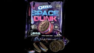 a container of oreo cookies featuring pink and purple icing inside and a rocket design stamped on them
