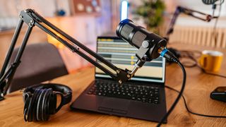 Podcast microphone in front of a laptop displaying recording software