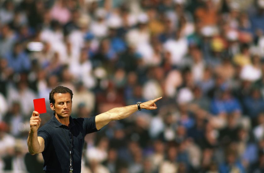 A football referee holding up a red card.