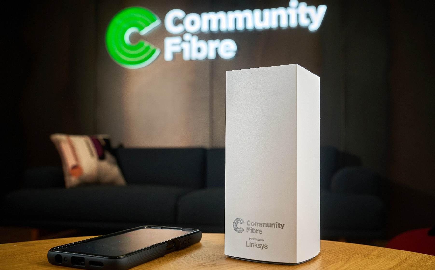 Router de Community Fibre sobre una mesa con el logo de la empresa al fondo