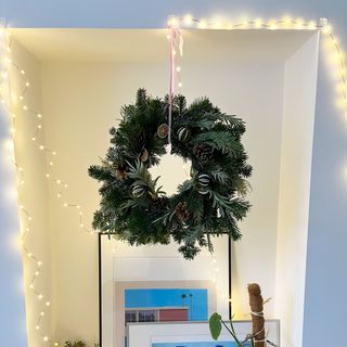 DIY natural wreath hung above lit up white mantel