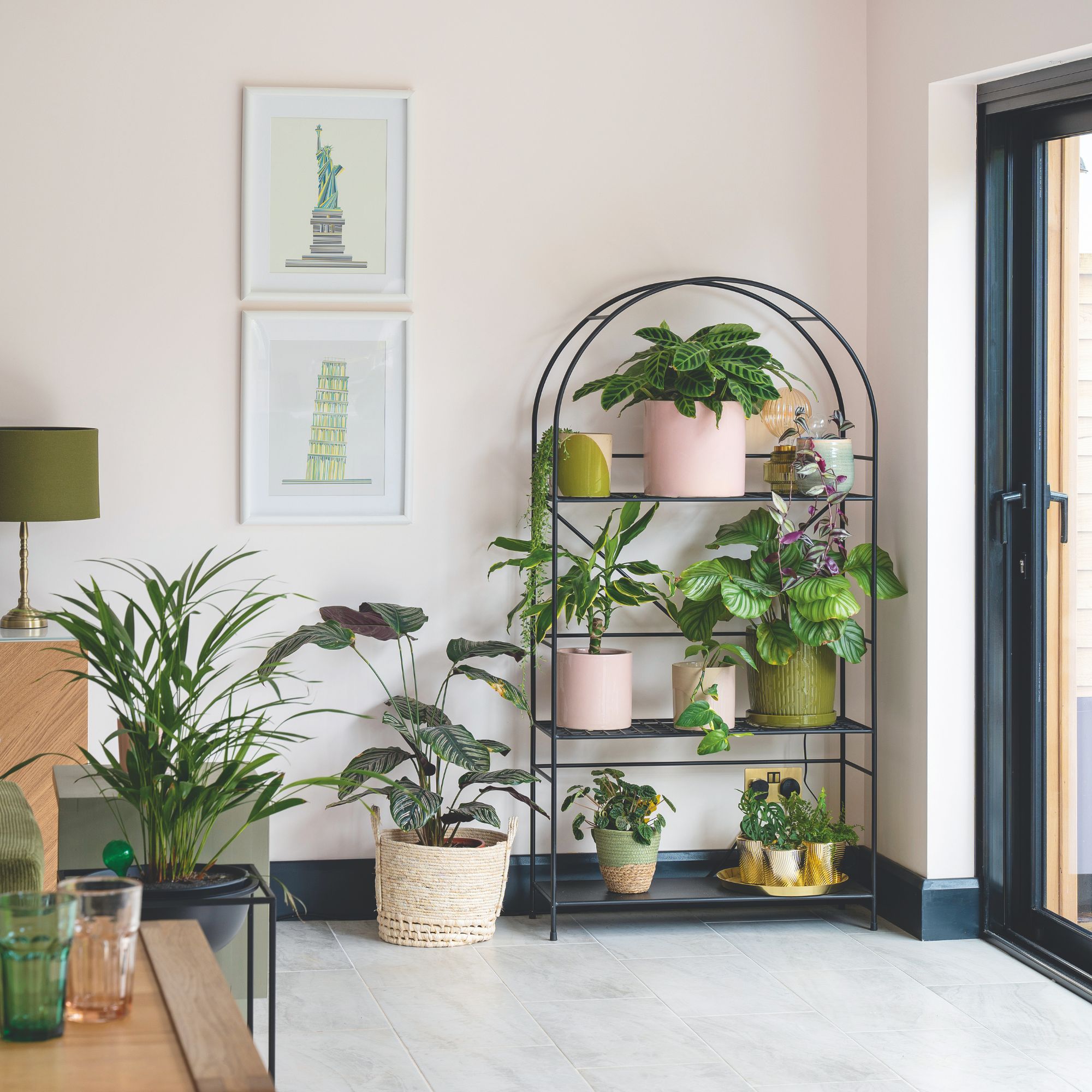 Área de comedor pintada de color rosa claro con una planta arqueada llena de plantas e imágenes en la pared