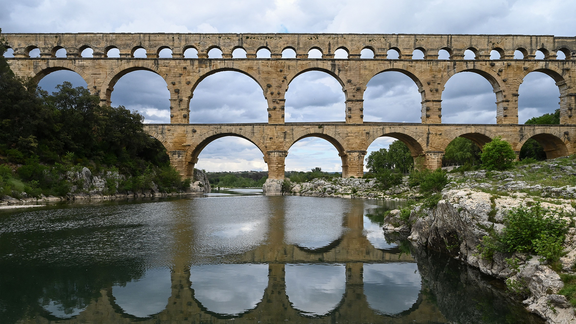 A large stone aqueduct is seen over a river.