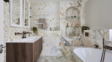 a master bathroom in palazzo oro marble, with large format tiles on the floor and one wall, and small hexagonal marble tiles on the other walls